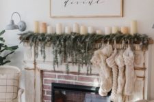 a built-in fireplace with an evergreen garland, lot sof stockings and pillar candles on the mantel