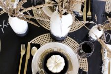 a chic black Thanksgiving tablescape with a dark runner, napkins, plywood placemats, wheat in a vase and gold cutlery