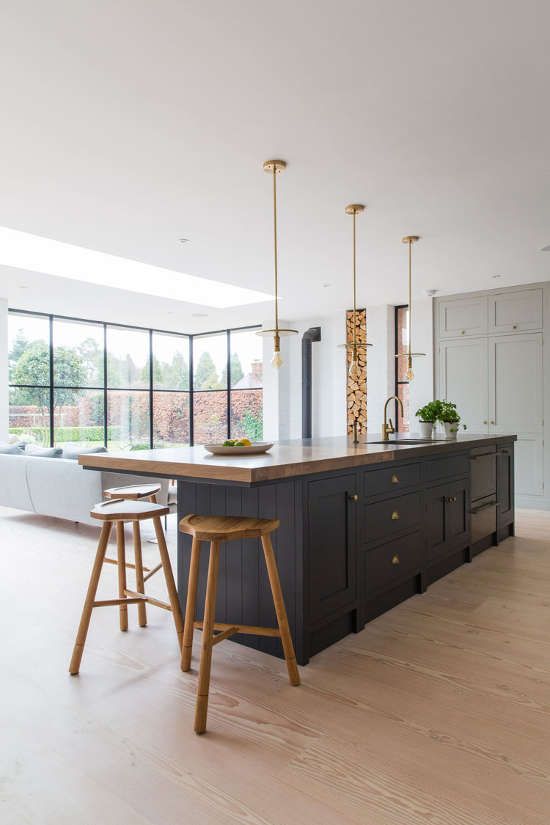 a contemporary light grey kitchen with a contrasting navy kitchen island and a small eating space with some stained wood stools