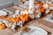 a cozy and bright fall centerpiece of white and orange pumpkins, pillar candles and cotton