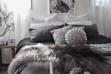 a cozy and moody bedroom with faux fur blankets, knit blankets and a rough wood bench is winter-reayd and very trendy