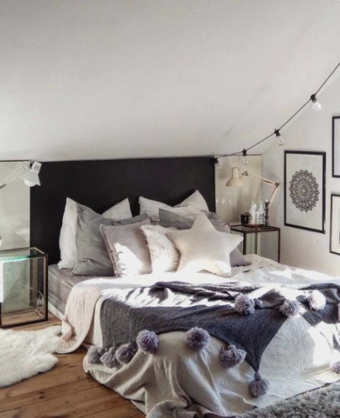 a faux fur rug, a knit blanket with large pompoms and some fur pillows and lights make the bedroom winter-ready