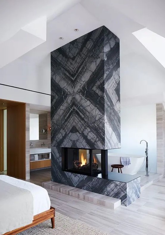 a grey marble slab fireplace separates the sleeping and bathing zone and makes them cozy and warm