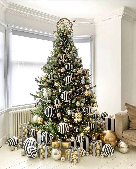 a jaw dropping modern Christmas tree decorated with black and white striped and gold large scale ornaments is amazing