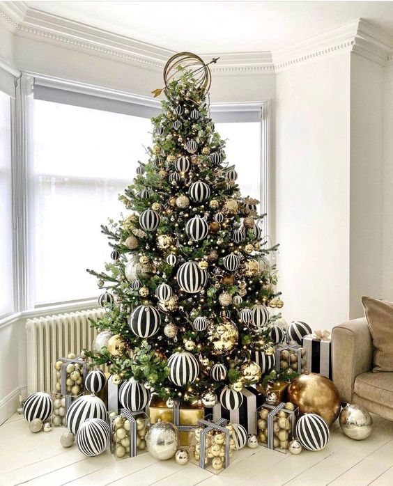 a jaw-dropping modern Christmas tree decorated with black and white striped and gold large-scale ornaments is amazing