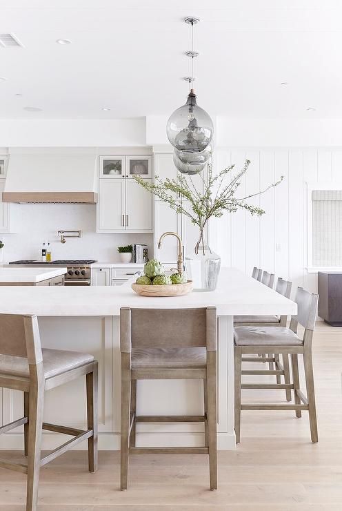 a light and airy neutral kitchen with touches of stained wood, with a large kitchen island that doubles as a dining table is cool