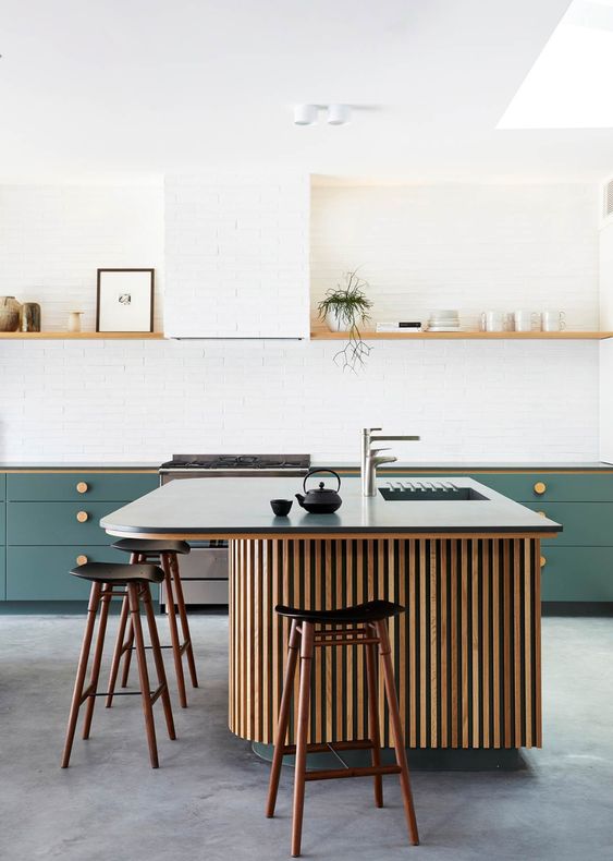 a lovely modern kitchen with green lower cabinets and an open shelf over them, a chic kitchen island with wooden slabs and a stone countertop, tall stools