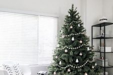 a minimalist Scandi Christmas tree decorated with white and silver ornaments, white pompom garlands and a basket plus black and white gift boxes
