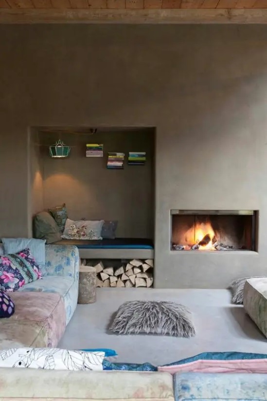 a minimalist fireplace nook with a built-in hearth and a built-in niche nook with books, a lamp and firewood under the bench is cozy