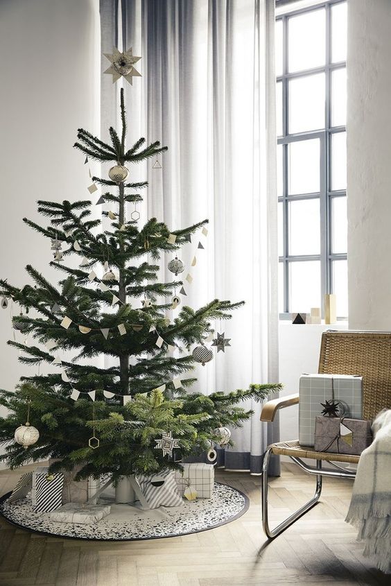 a modern Christmas tree decorated with silver and black and white ornaments, with paper buntings and matching black and white gift boxes