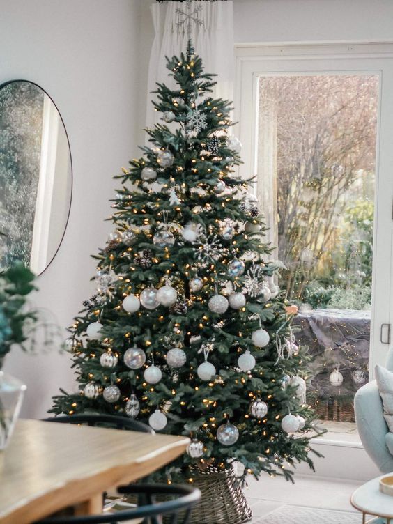 a modern Christmas tree styled with white, silver and clear ornaments and with lights and snowflakes is a chic idea