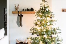 a modern Christmas tree with black and white ornaments, with lights and a gold star topper plus a windowpane tree skirt