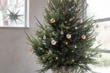 a modern Christmas tree with silver, copper and gold ornaments and lights plus a woven basket is a gorgeous idea to rock
