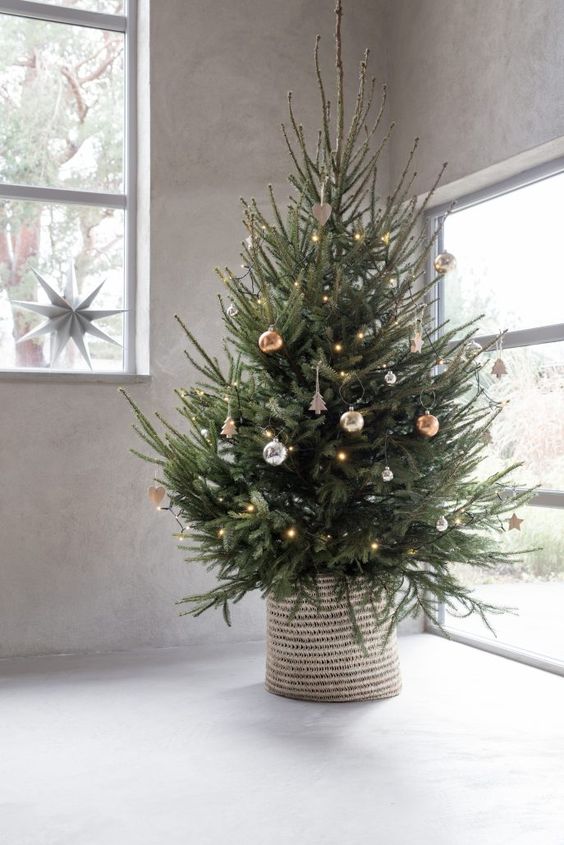 a modern Christmas tree with silver, copper and gold ornaments and lights plus a woven basket is a gorgeous idea to rock