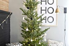 a modern Christmas tree with white and black ornaments and lights is a stylish idea that will fit a Scandinavian space, too