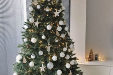 a modern Christmas tree with white baubles and stars, pinecones and lights is a chic idea with a trendy feel