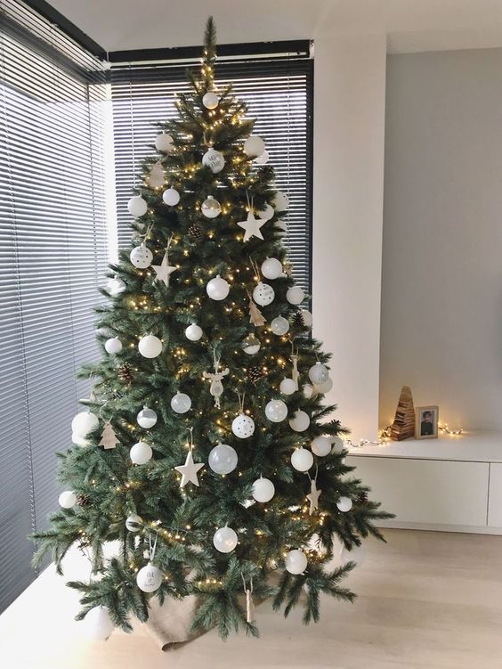 a modern Christmas tree with white baubles and stars, pinecones and lights is a chic idea with a trendy feel