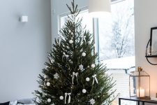 a modern Christmas tree with white baubles, snowflakes and bows and nothing else looks clean, chic and strikes with its natural beauty