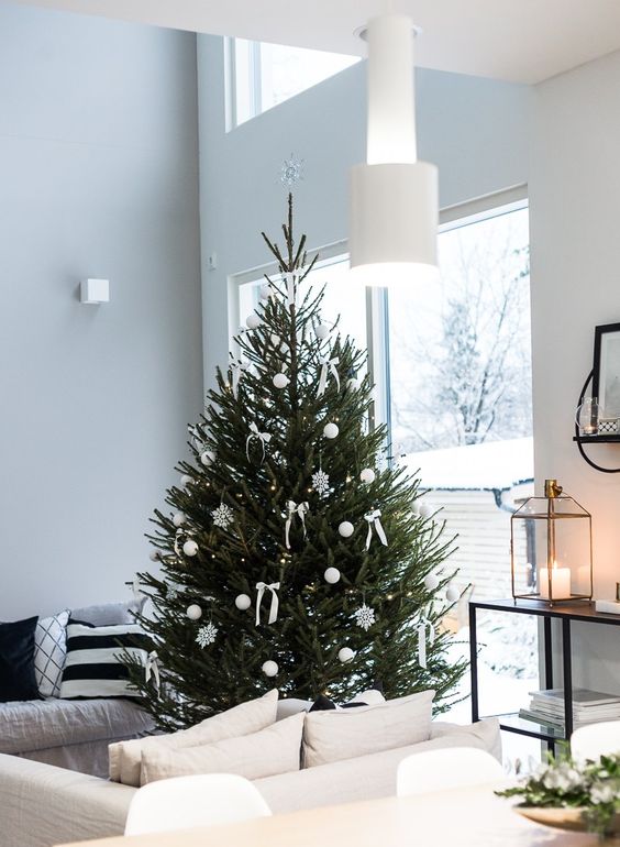 a modern Christmas tree with white baubles, snowflakes and bows and nothing else looks clean, chic and strikes with its natural beauty