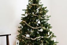 a modern Nordic Christmas tree with lights, wooden beads, white clay ornaments and baubles is a stylish idea