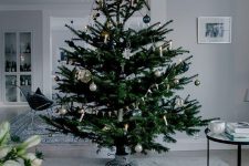 a modern Scandi Christmas tree with navy, silver, green and clear ornaments plus lights and buntings is a beautiful idea