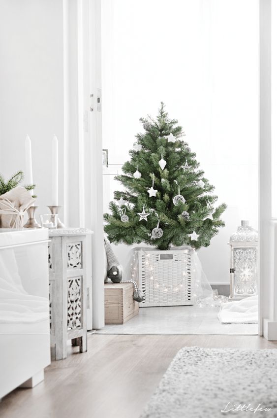 a modern Scandi Christmas tree with white and clear ornaments, lights hanging on the basket and some tulle is a chic odea