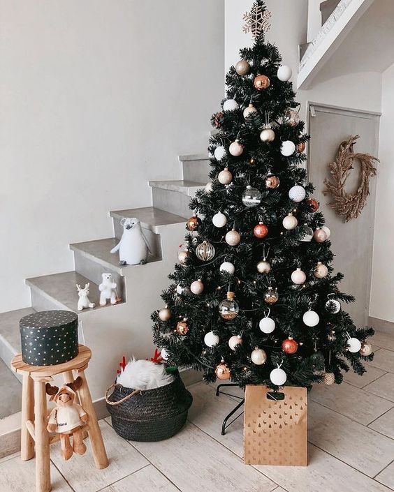 a modern dark green Christmas tree decorated with clear, green, red and gold ornaments plus a snowflake tree topper