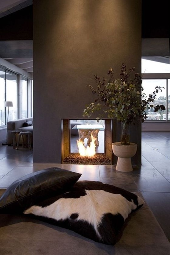 a modern double-sided fireplace done of grey concrete looks really spectacular and very chic