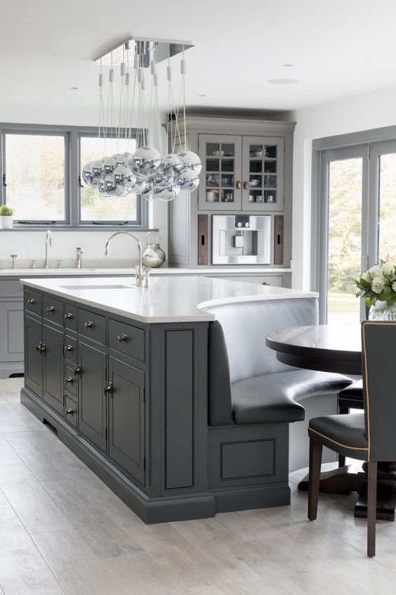 a modern graphite grey kitchen with a large kitchen island that shows off a banquette seating integrated right in it