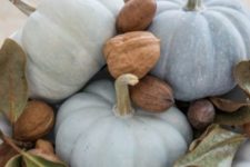 a natural centerpiece of a white bowl with milk paint pumpkins, nuts and foliage is great for Thanksgiving