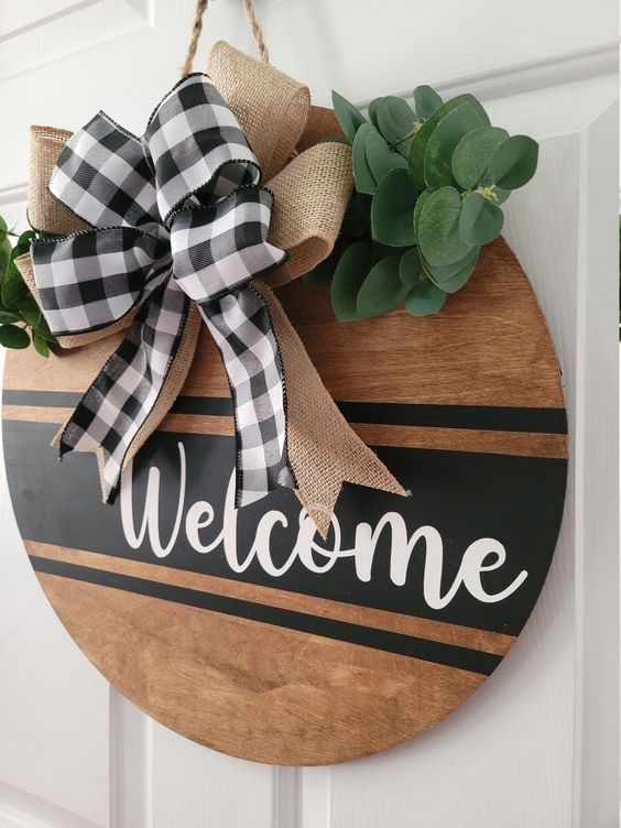 a plywood door hanger with a burlap and plaid bow and greenery is a lovely alternative to a usual Thanksgiving wreath