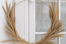 a simple and modern Thanksgiving wreath made of a metal frame and some wheat is a stylish idea for decor