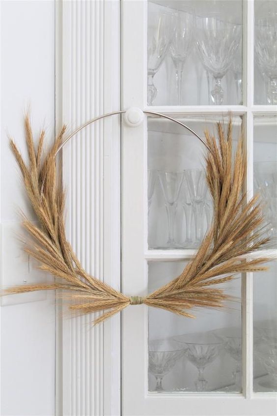 a simple and modern Thanksgiving wreath made of a metal frame and some wheat is a stylish idea for decor
