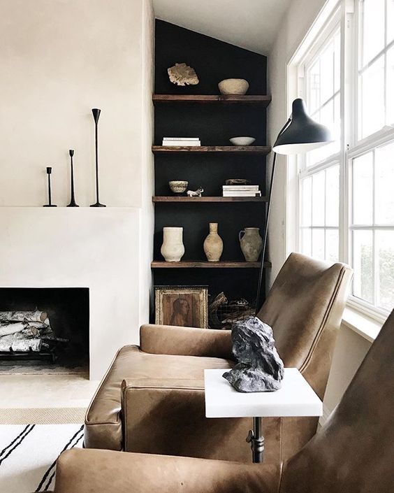 a soothing living room with a built-in fireplace, built-in shelves and brown leather chairs, some black touches