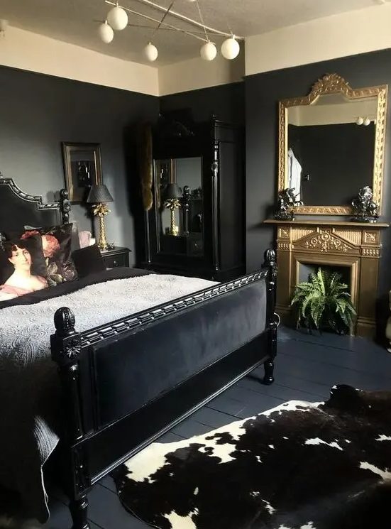 a sophisticated bedroom with black walls, a black bed and mirror, a gold fireplace and a mirror and some plants and art