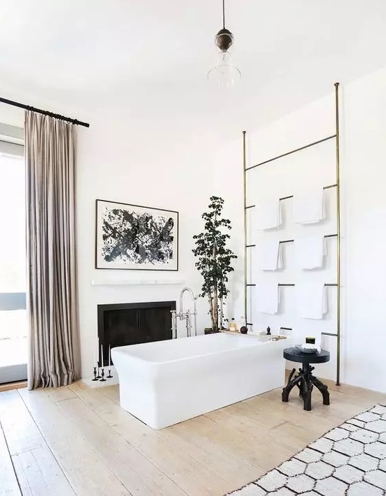 a sophisticated modern bathroom with a fireplace, a rectangular but, a large ladder for towels, a black carved table, a potted plant and blush curtains
