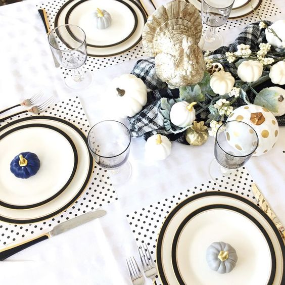 a stylish Thanksgiving tablescape with polka dot placemats, black edge plates, pumpkins, a plaid runner and greenery