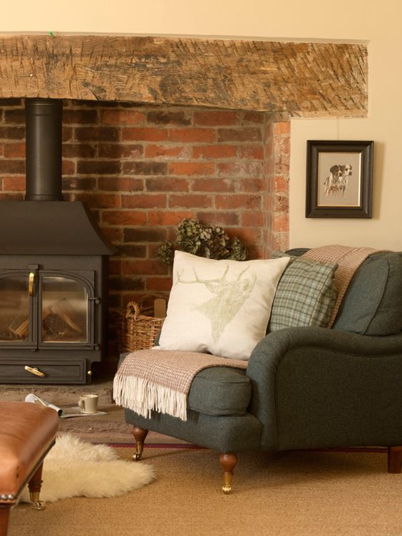 a vintage space with a vintage hearth, a grey double chair with pillows, a basket and greenery is a chic idea to rock