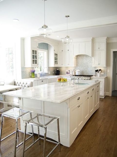 a white farmhouse kitchen with shaker style cabinets, a shiny backsplash, a large kitchen island with an eating space and acrylic stools