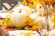an all-natural Thanksgiving tablescape with a bold plaid tablecloth, neutral porcelain, bold leaves and white pumpkins