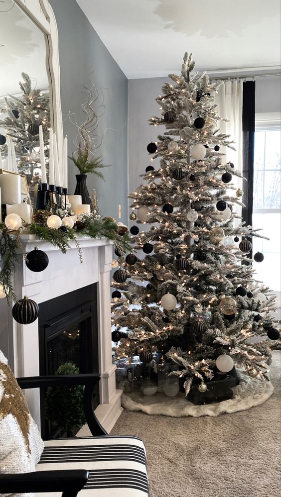 an elegant modern flocked Christmas tree with white, silver and black striped ornaments plus gift boxes is cool