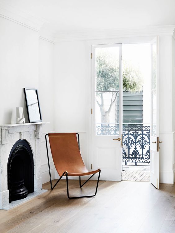 an elegant nook with a stone fireplace and a mantel plus a butterfly leather chair is an inviting and welcoming space