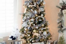 an exquisite Christmas tree with black, white and gold ornaments and cool striped ribbons and lights plus a gold snowflake topper