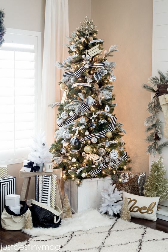 an exquisite Christmas tree with black, white and gold ornaments and cool striped ribbons and lights plus a gold snowflake topper