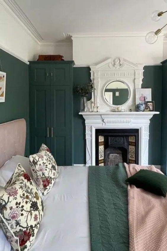 an eye-catchy bedroom with dark green walls, a wardrobe, a fireplace, a pink bed with green and pink bedding