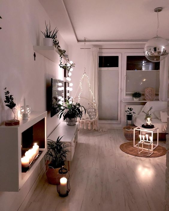 candles in candleholders and lanterns, lights over the chair and on the shelf make the space lit up and cozy