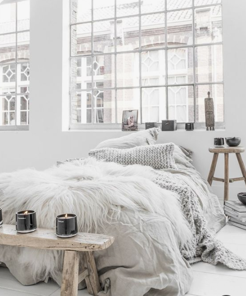 faux fur, candles, bowls and a rough wooden bench plus a knit pillow are ideal for a winter-like Scandinavian bedroom