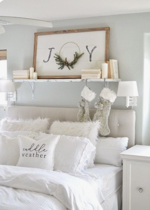 faux fur stockings and pillows, a Christmas sign and some pillar candles make the white bedroom super cozy and chic