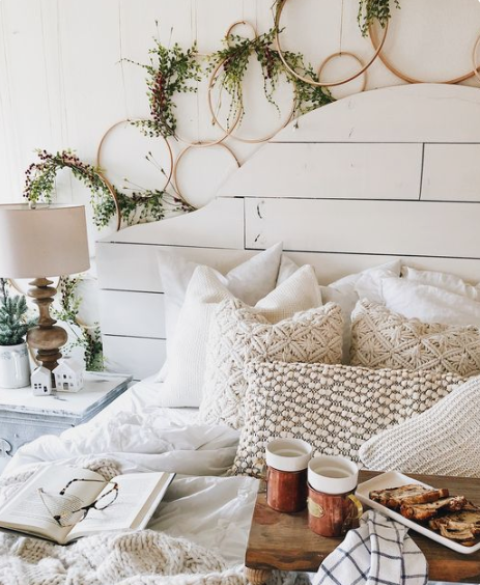 lots of hoop wreaths with greenery, knit and crochet pillows and blankets give the bedroom a cool and cozy winter look