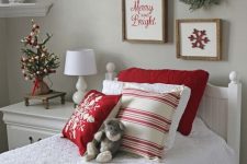 Christmas printed bedding and pillows, a tiny tabletop Christmas tree with gold, red and green Christmas ornaments, some art and a wreath